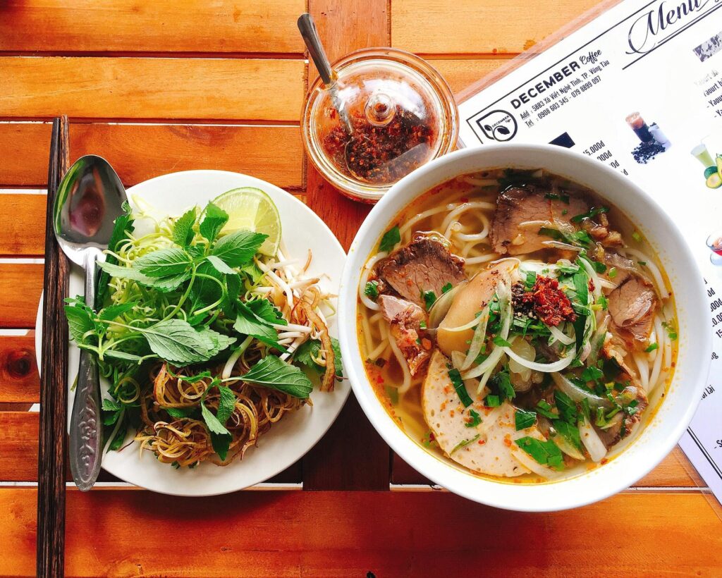 Bowl of Bun Bo Hue with fresh herbs
