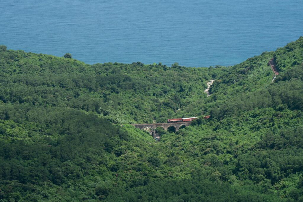 Train crossing a green pass by the ocean
